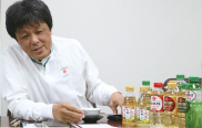 新旧製品を前にPETボトル透明化を語る佐々木本部長